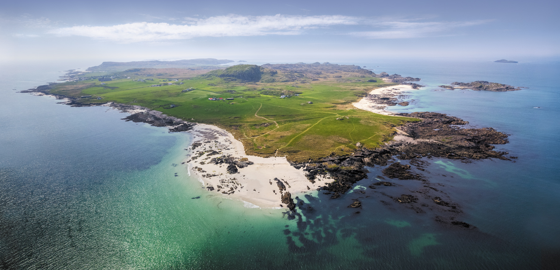 Aerial panorama of the Isle of Iona, green fields and white sand beaches surrounded by turquoise sea